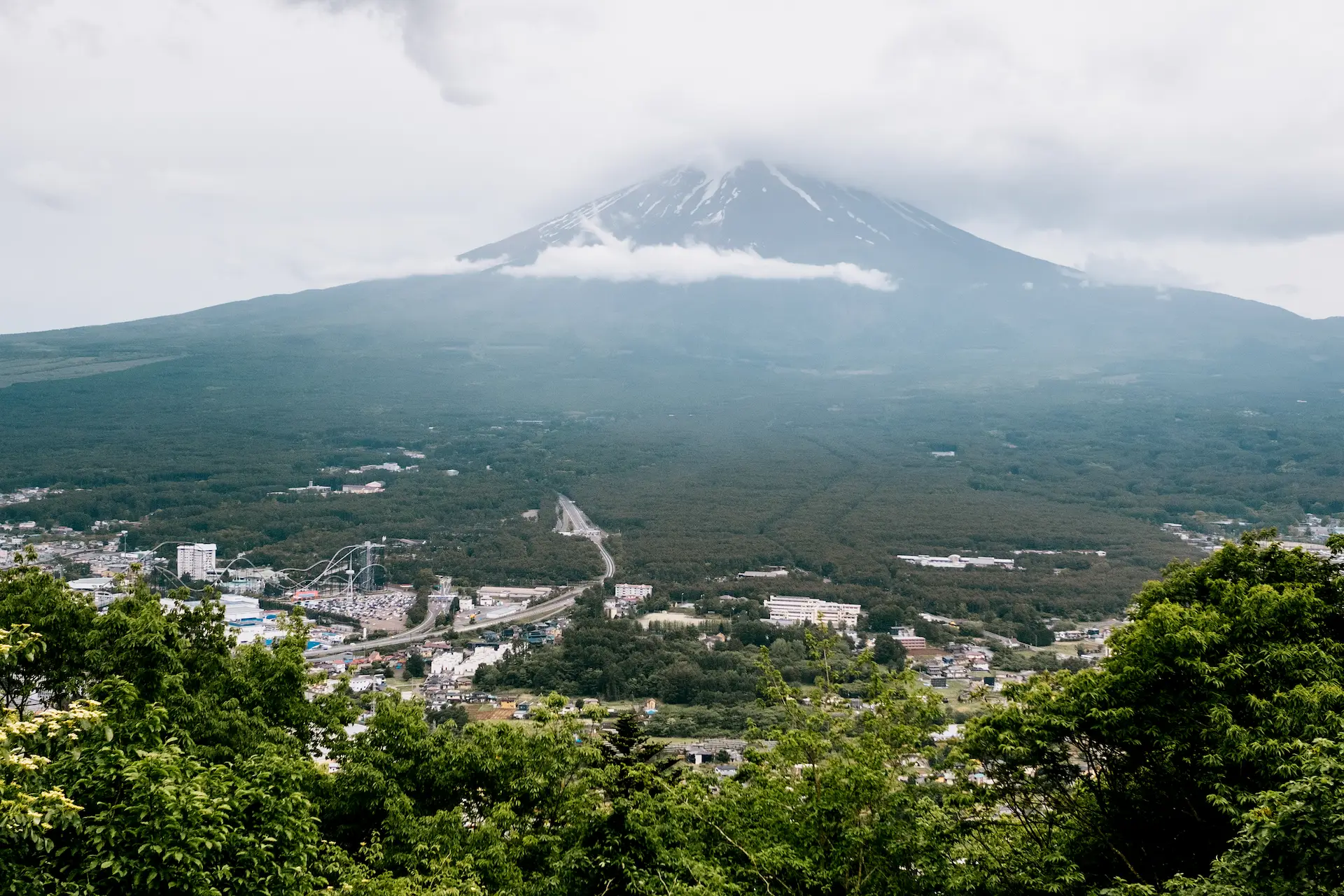 A moody landscape view of Mount Fuji partially shrouded in heavy storm clouds, taken from the Mt. Fuji Panoramic Ropeway observation deck during a Japan travel itinerary.