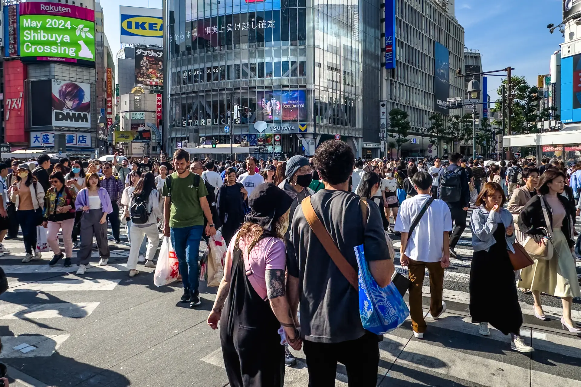 A bustling street-level view of a massive crowd of people walking across the Shibuya Crossing intersection in Tokyo during a Japan travel itinerary.